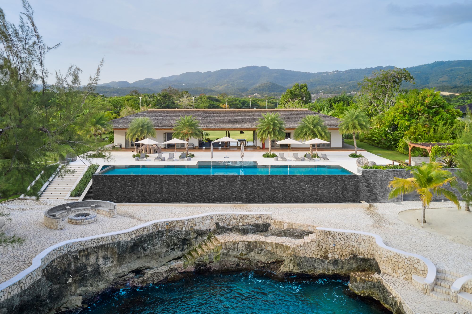 poolhouse, pool house, tropical, cove, cliff, mountains, pool, infinity pool, beach, tropical, landscape, lounge, entertainment, relaxation, umbrella, outdoor, palm trees, stone