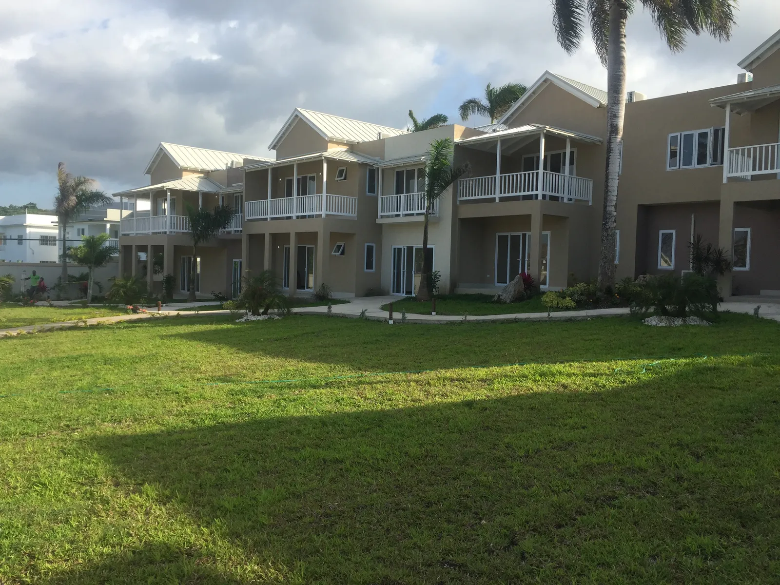 elevated view toward the hills, pastel blocks with metal roofs and balconies arranged around a broad green.