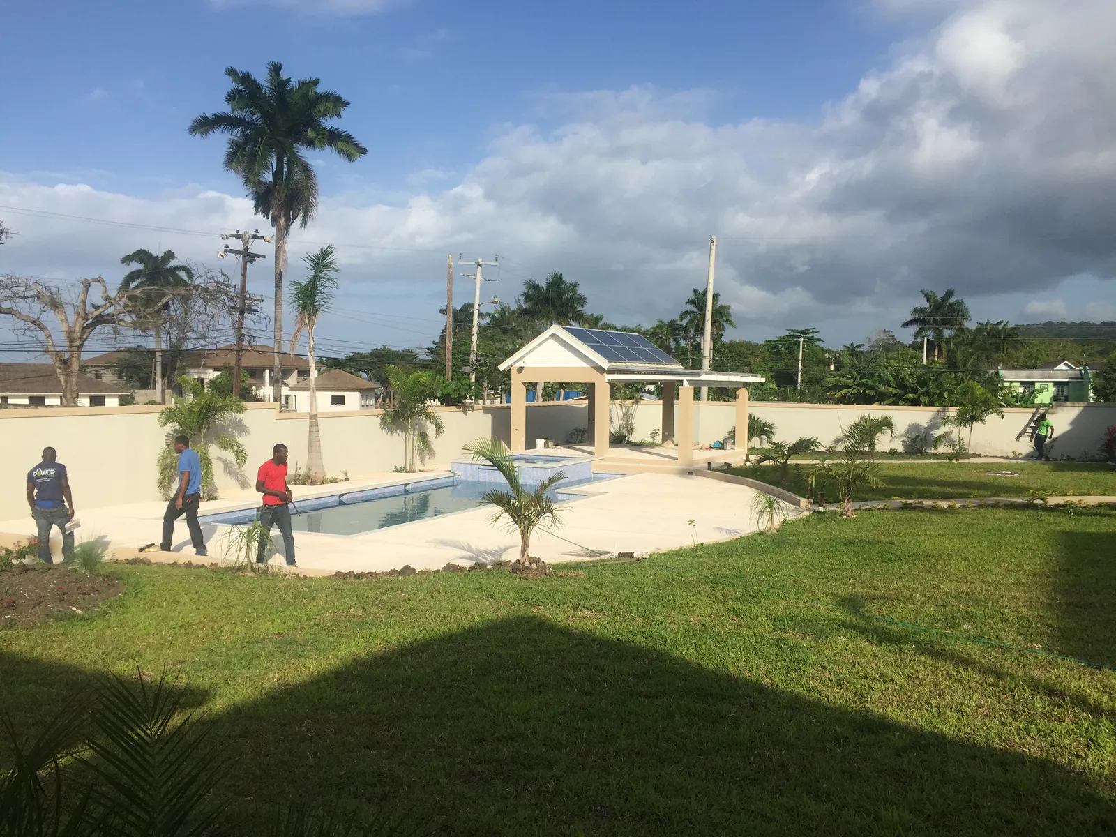 rooftop solar arrays and PV carport above a paved service court, metal roofs and utility lane below.