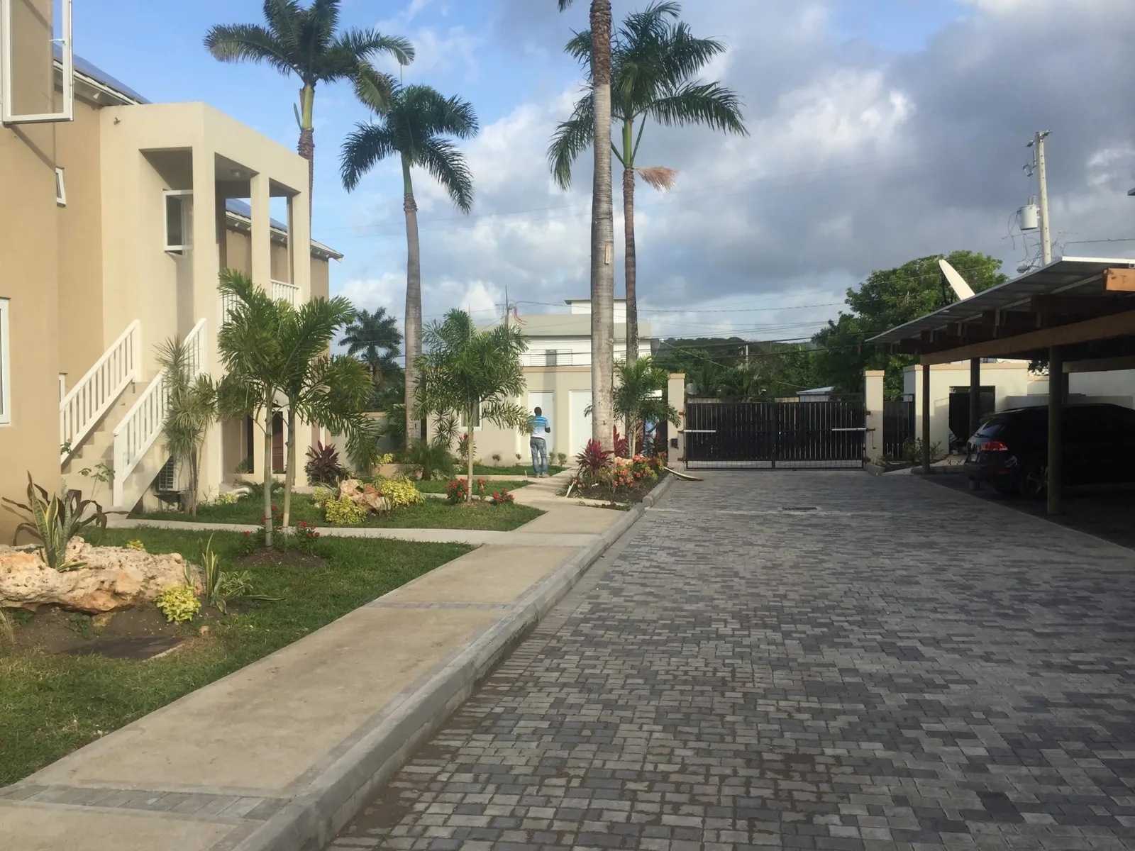 rectilinear pool with raised spa and small gazebo inside a walled compound, young palms at the deck edge.