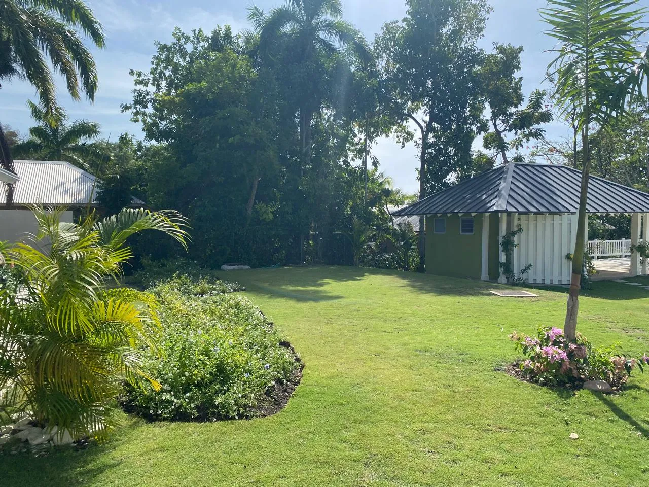 central lawn with small green pavilion and surrounding trees, landscaped community open space.