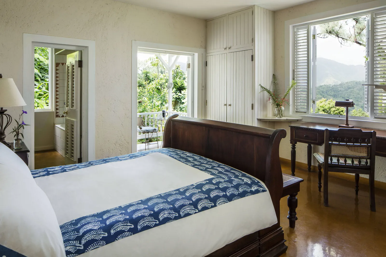 sleigh-bed cottage room with desk and open shutters to mountain view, doors to bath and verandah.
